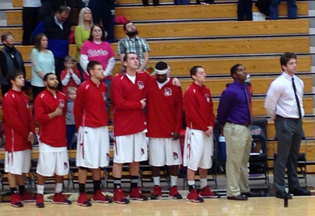 At Saturday's game, Joe Godfread (front and third from the left) leans on a fellow teammate for support during a moment of silence for Godfread's mother Rachelle. She was fatally shot at Martin's Super Market in Elkhart last Wednesday. (Preface photo: Neil King)