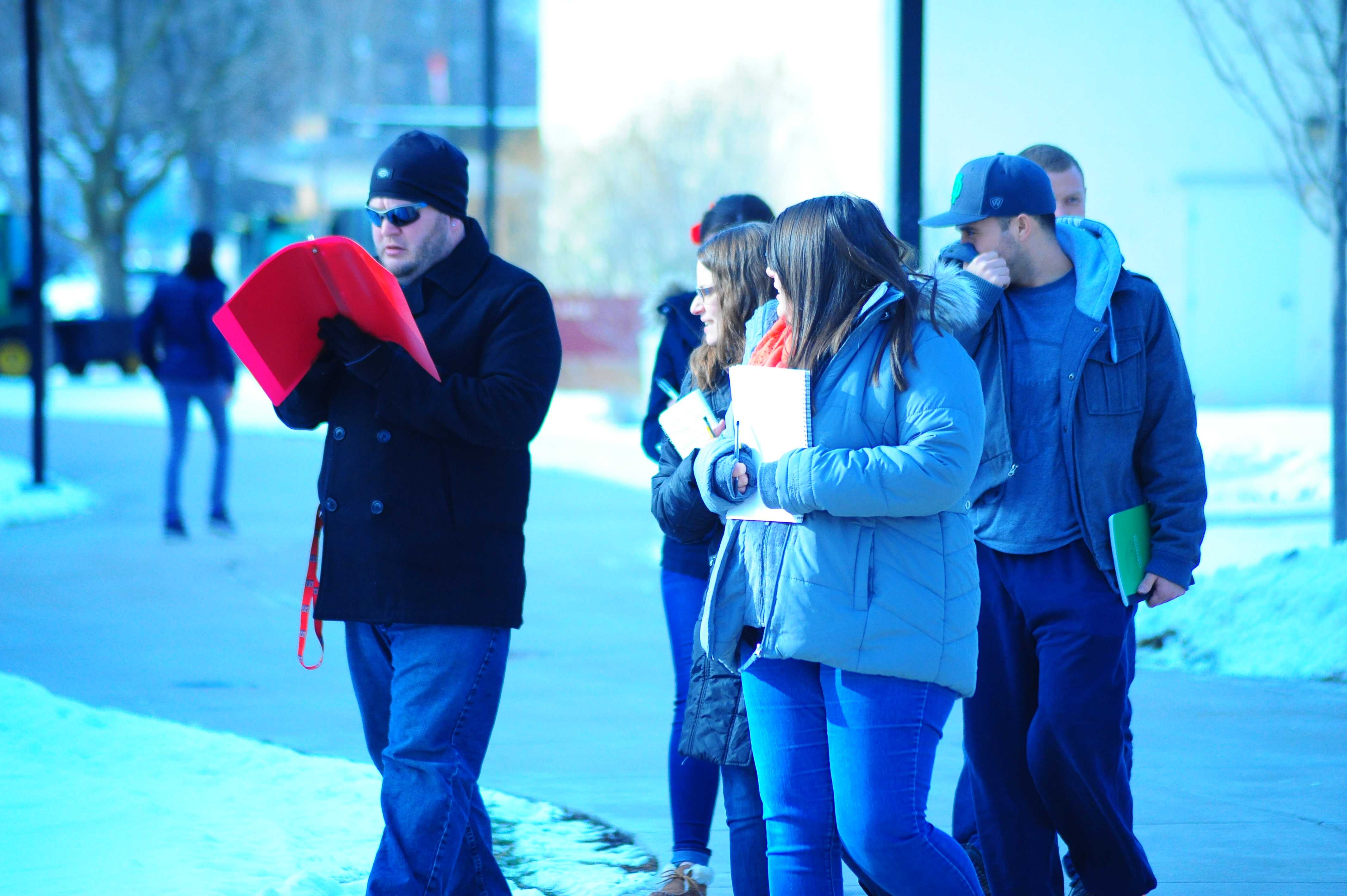 A group of students walk through the campus mall. One student shields his nose from that infamous, mysterious smell. Photo Credit/Michael Montana