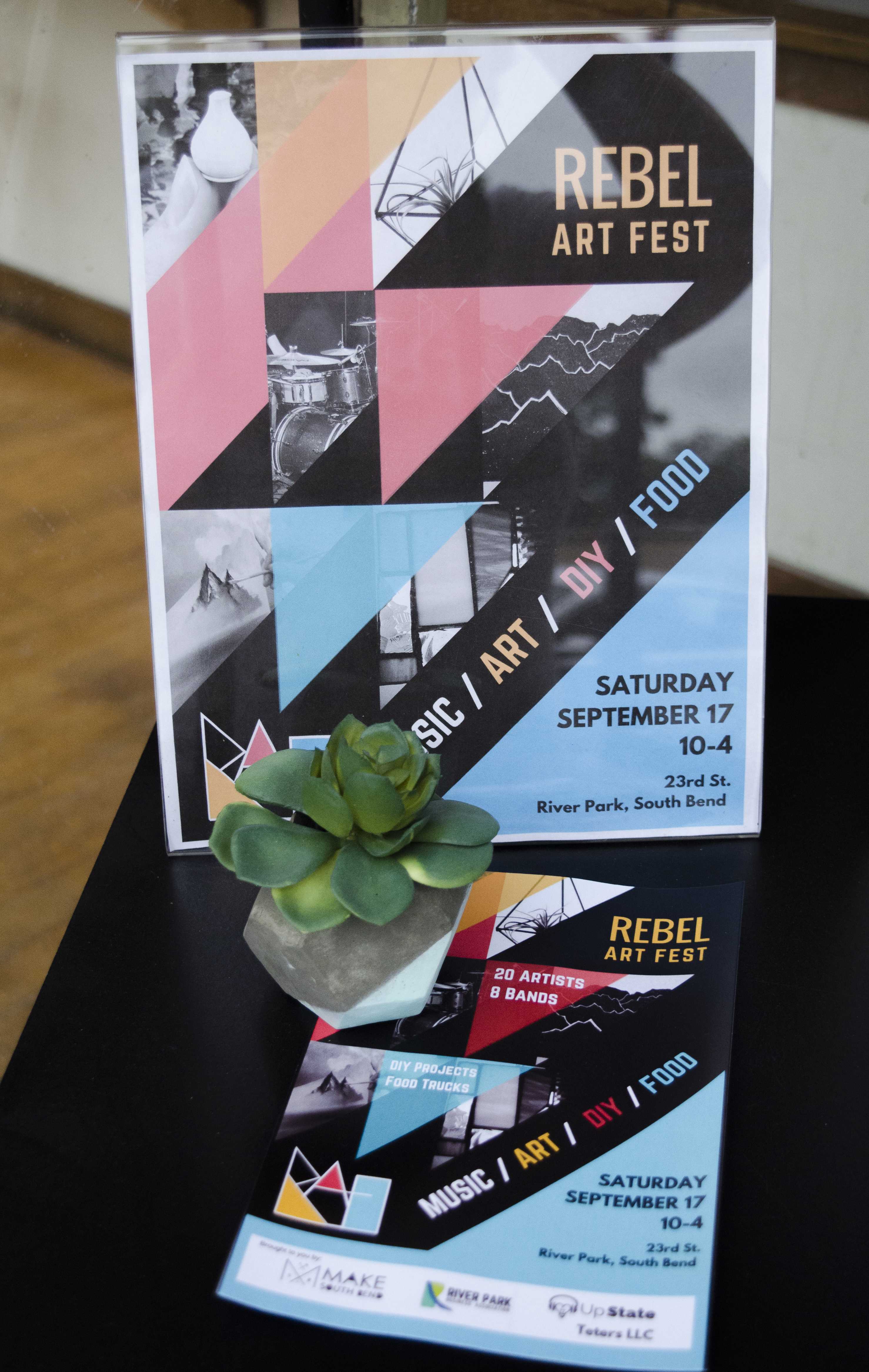 The flyer for Rebel Art Fest sits displayed at MAKE South Bend along with an example of a DIY that will be available at the festival. PHOTO/Leah Fick
