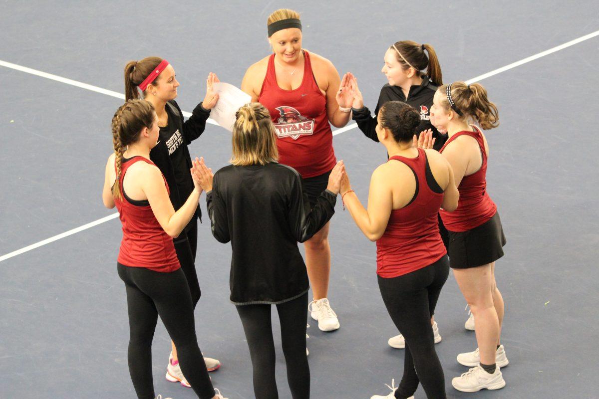 The women’s team alongside coach Jessica Simeri prepare for their first match of the program’s history.

Photo/Casey McDonald
