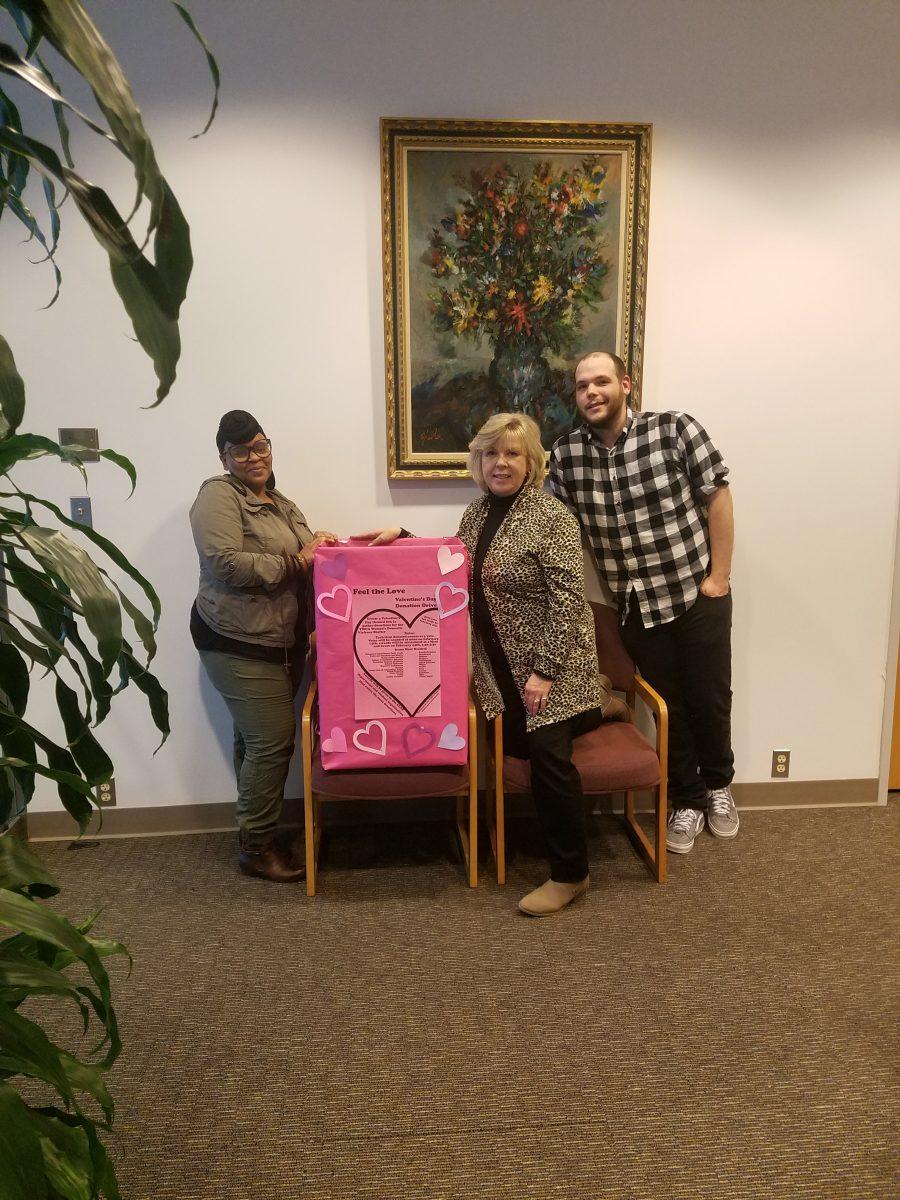 From left to right Ebony Haynes, Secretary to the Dean; Linda Schultz-Heidrich, Office of the Dean; Nick Wort, Assistant to the Associate Dean, posing with one of the donation boxes for the drive. PHOTO BY/EVA MONHAUT
